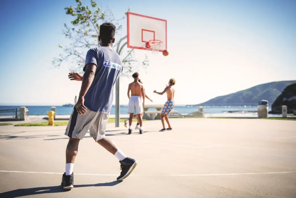 Image of four men playing basketball near the ocean