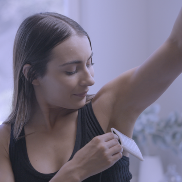 A picture of a woman putting one of the Fischer iontophoresis device underarm attachments under her arm to treat axillary hyperhidrosis aka excessive sweating of the underarms