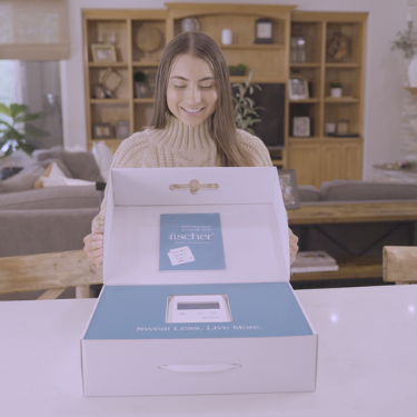 In a charming home setting, we encounter a young woman with brown hair, her cheerful smile lighting up the room as she unveils the contents of a package housing RA Fischer Co.'s "The Fischer," the original metal-free iontophoresis device meticulously designed to tackle hyperhidrosis or excessive sweating.