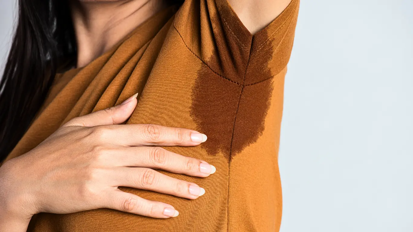 In this portrayal, we encounter a woman donned in an orange shirt who raises her arm, inadvertently revealing a perspiration stain on her armpit. The presence of this stain underscores the challenge she faces with axillary hyperhidrosis, a condition characterized by excessive underarm sweating. Fortunately, the Fischer iontophoresis device offers a potential solution for her, providing a means to effectively manage this condition and regain confidence. This poignant image serves as a powerful reminder of the impact that innovative treatments like the Fischer device can have on individuals dealing with hyperhidrosis.