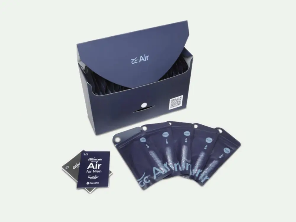 Picture of a box of GentleCath Air catheters from RA Fischer next to five catheters in their packets and a copy of the manual for GentleCath Air for Men. Box reads "GC Air." There are 5 of the catheters in front of the box and a manual next to them. The manual reads "GentleCath - Air for men with FeelClean technology - ConvaTec"