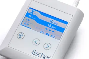 A captured image provides an in-depth look at RA Fischer's groundbreaking 'The Fischer' Device, highlighting the central element of this specialized iontophoresis device, referred to as the 'main control unit.' This meticulously crafted device is tailored specifically for addressing the challenging condition of hyperhidrosis, which involves excessive sweating. The 'main control unit' showcases a sleek white rectangular design, housing a grey screen adorned with strategically placed buttons labeled 'SET' and accompanied by directional arrows for precise control. In the lower right corner, the distinct logo of the Fischer device adds a touch of brand identity to this innovative solution for managing hyperhidrosis. The composition of the photograph is thoughtfully set to provide a comprehensive view of this device's features and functionality.