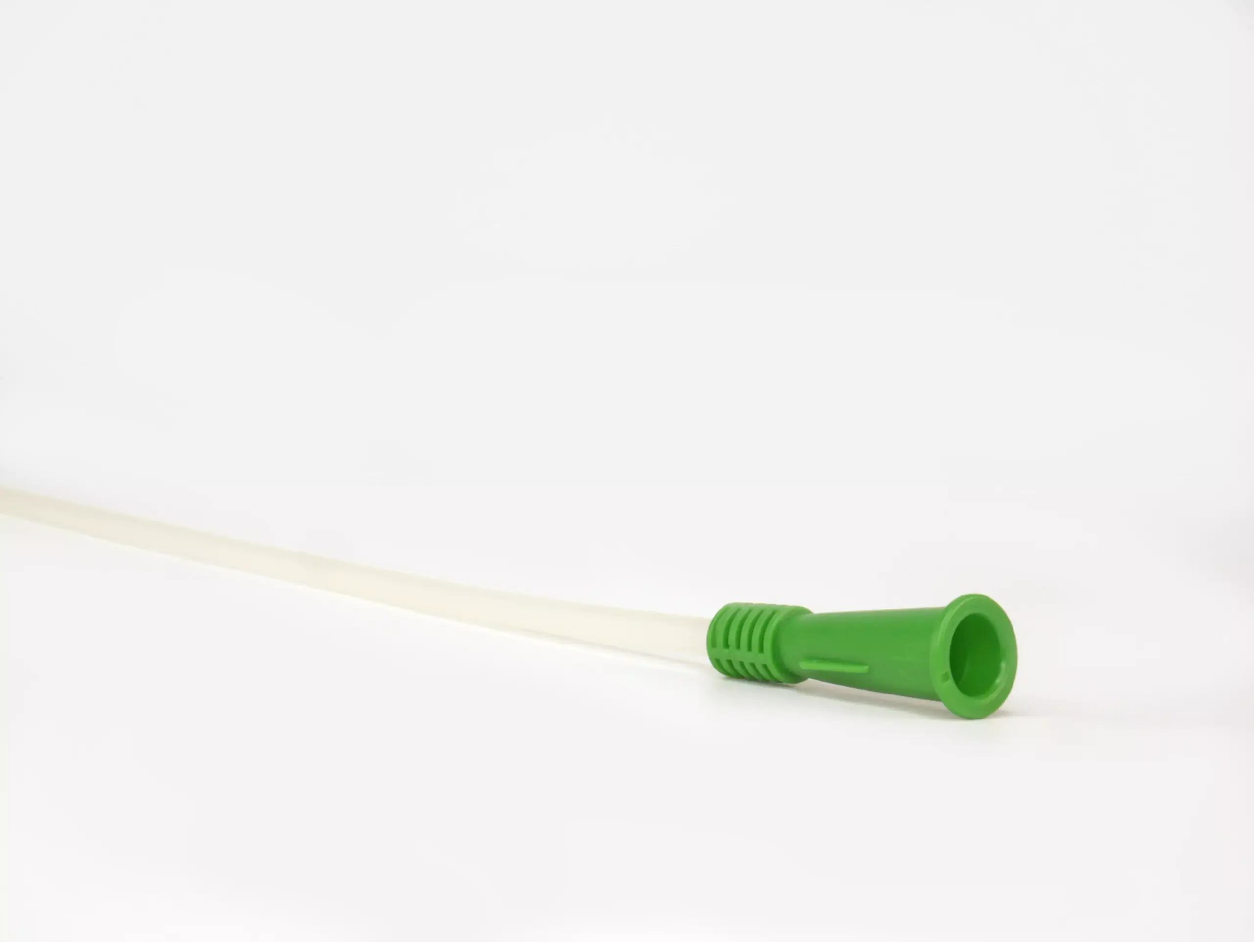 Detailed close-up of the distinctive green grip on a RA Fischer Co. Cure brand catheter, set against a white backdrop. [ Personalized urology care ]