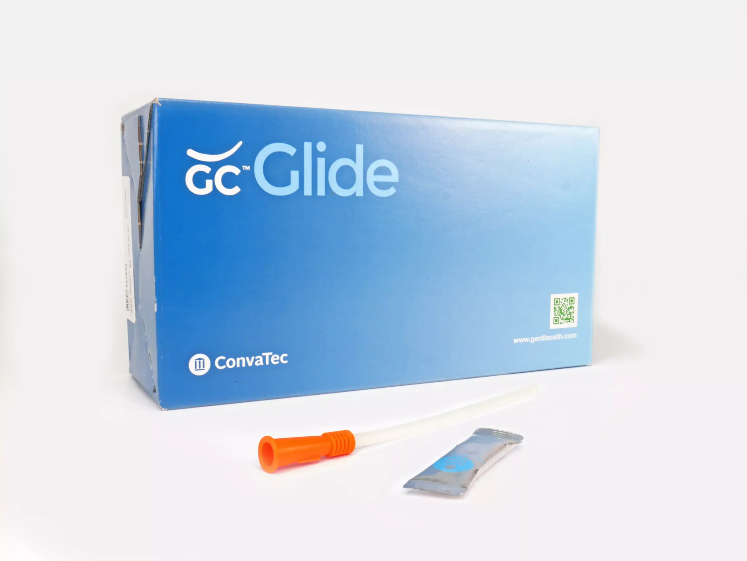 An image featuring a box of 30 GentleCath Glide catheters from RA Fischer. Positioned in front of the box is one of the catheters with an orange gripper, accompanied by a lubrication or water packet. The box displays the labels "GC Glide," "Convatec," "www.gentlecath.com," and a QR code