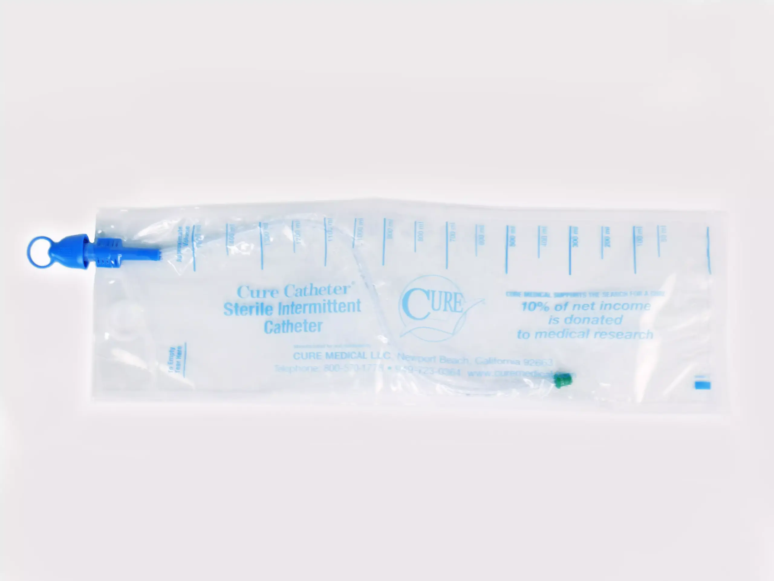Close-up photograph of one of RA Fischer Co.'s Cure Catheters, blue on clear bag. Bag reads "Cure Catheter. Sterile Intermittent Catheter. Cure. 10% of net income is donated to medical research."