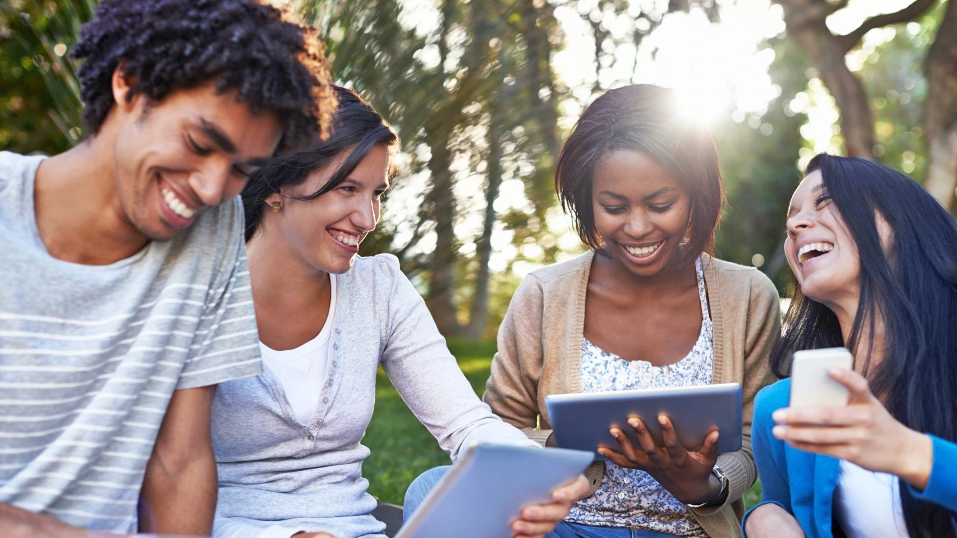 Picture of four younger patients looking at a tablet and a phone. They are smiling