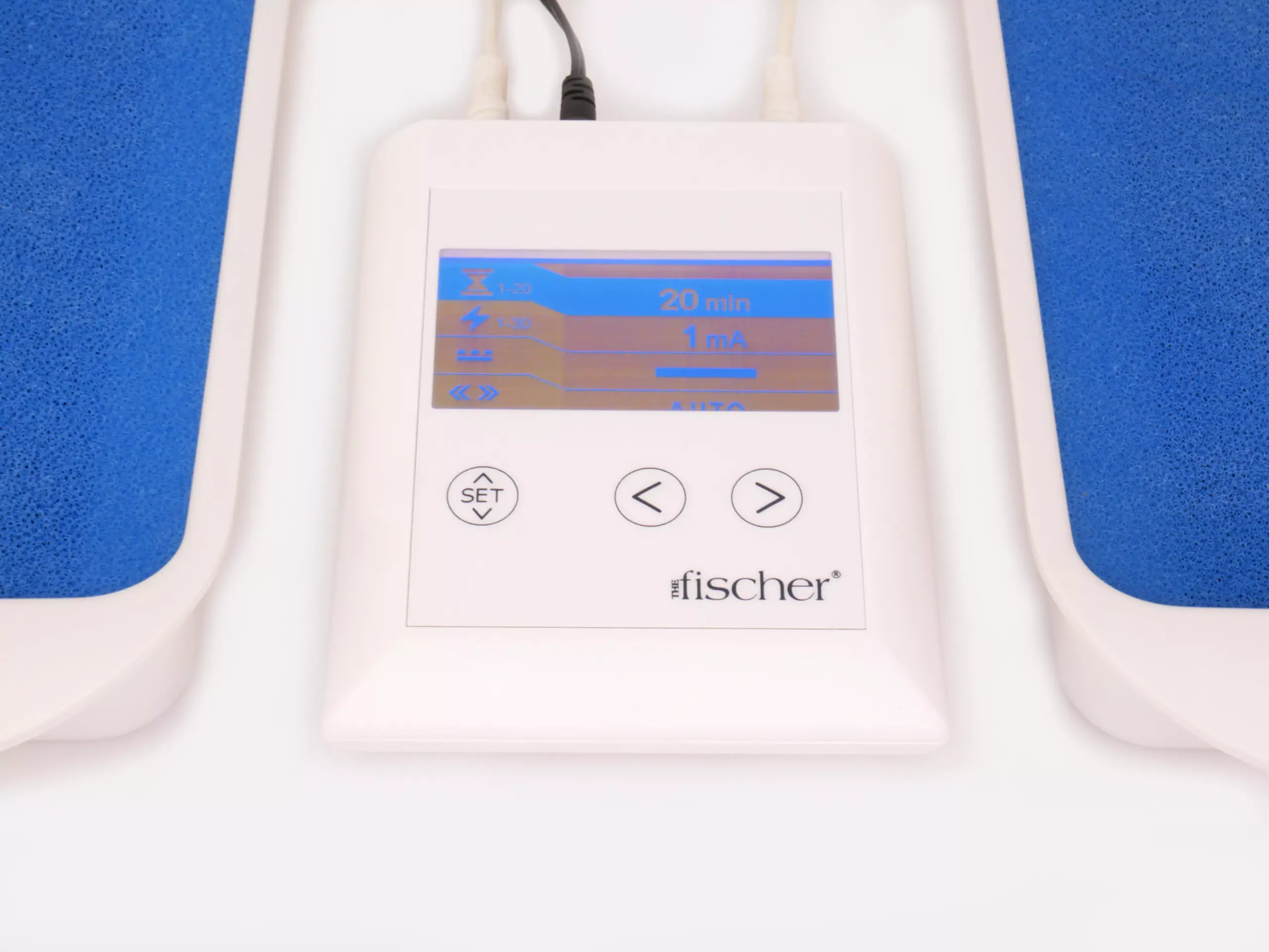 Photograph showcasing the white, rectangular 'main control unit' of RA Fischer's 'The Fischer' Device—an iontophoresis device designed for the treatment of hyperhidrosis (excessive sweating). The Fischer iontophoresis device is characterized by its white and rectangular shape with a blue and grey screen. On the left side of the device, there is a button labeled 'SET,' while two buttons on the right are represented by arrows. The Fischer device logo is placed in the bottom right corner. It is in between the water bath trays that have the blue ph-balancing foam and metal-free electrodes inside. [ Iontophoresis Device for Sweating ]