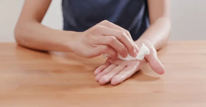 A person with hyperhidrosis using a paper towel to clean their hands, ensuring cleanliness and hygiene.