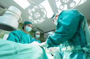 Surgeons in green scrubs performing Endoscopic thoracic sympathectomy (ETS) surgery in an operating room
