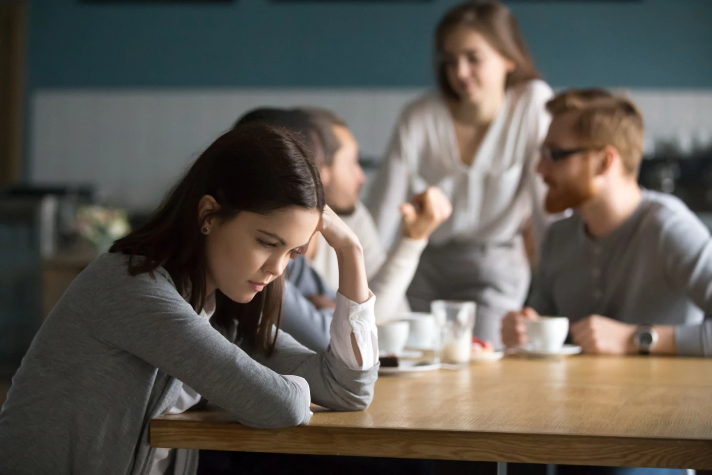 Woman seated at table with head down. [ Hyperhidrosis Treatment at Home ]