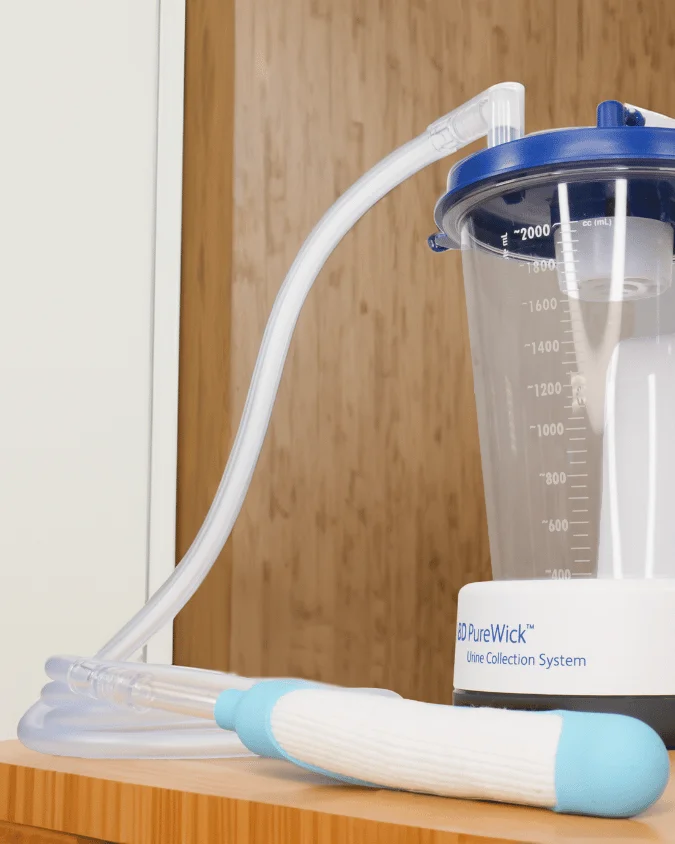 Image of the BD PureWick™ Female External Catheter – Wick and main unit on desk, available through RA Fischer Co with possible Medicare coverage (†When ordered through RA Fischer Co for eligible patients.)